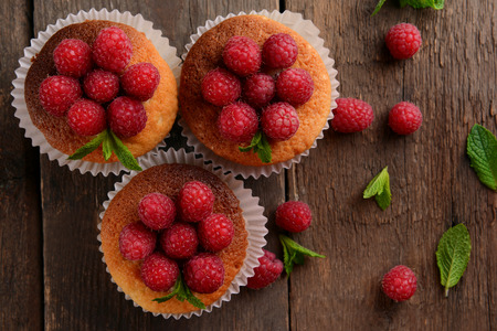 Delicious cupcakes with berries and fresh mint on wooden table close up