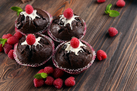 Delicious chocolate cupcakes with berries and fresh mint on wooden table close upの写真素材