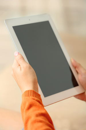 Female hand holding PC tablet on home interior backgroundの写真素材