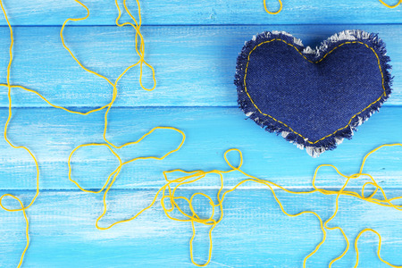 Denim heart and thread on wooden backgroundの写真素材