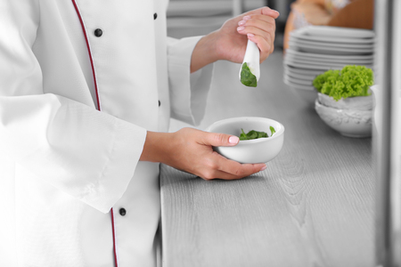 Cook hands with mortar with herbs on bright backgroundの写真素材