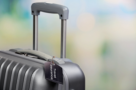 Suitcase with TRAVEL INSURANCE label on light blurred backgroundの写真素材