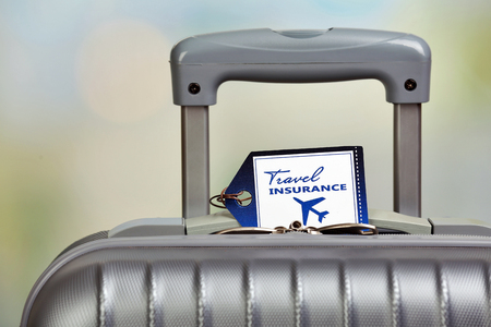 Suitcase with TRAVEL INSURANCE label on light blurred backgroundの写真素材