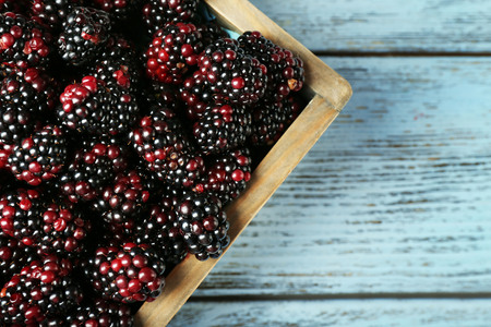 Heap of sweet blackberries in box on table close up