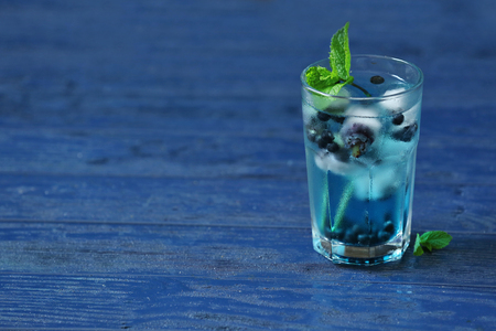 Glass of cold refreshing summer drink with berries and ice cubes on table close upの写真素材
