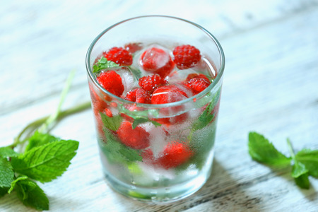 Glass of cold refreshing summer drink with berries and ice cubes on table close upの写真素材