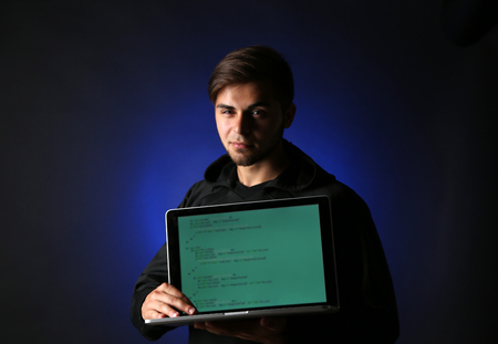 Hacker with computer and laptop on colorful dark backgroundの写真素材
