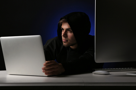 Hacker with computer and laptop on dark background の写真素材