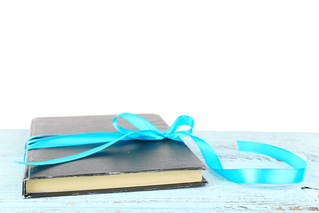 Book wrapped with color ribbon on table isolated on whiteの写真素材