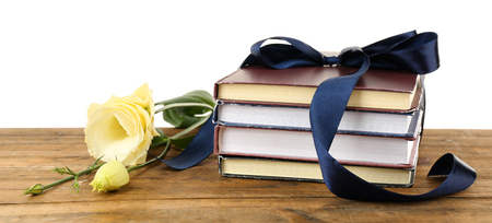 Stack of books with ribbon and flowers isolated on whiteの写真素材