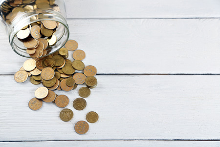 Coins in money jar on wooden background