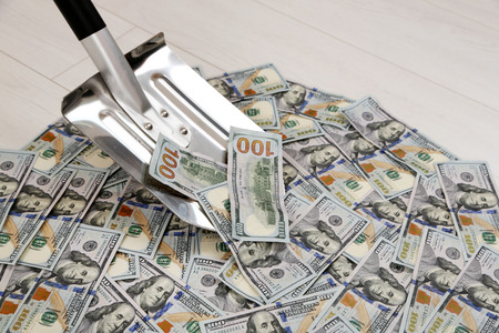 Shovel lifts dollar bills on floorの写真素材
