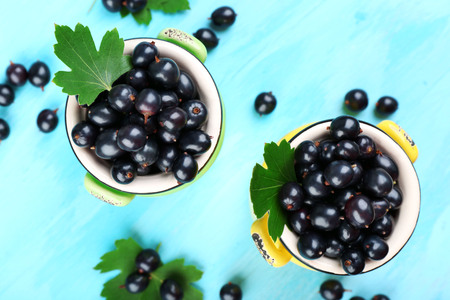 Top view of ripe black currants in metal mugs on wooden backgroundの写真素材