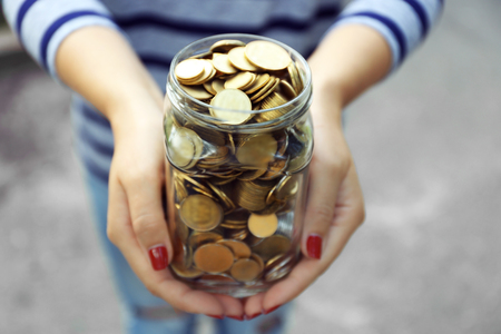 Woman holding money jar with coins outdoorsの写真素材