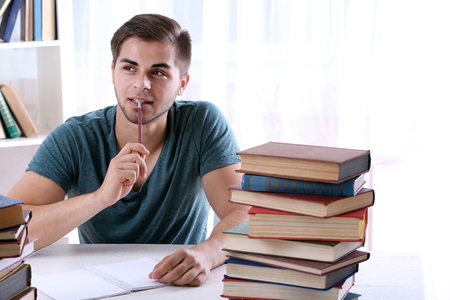 Young man reading book at table in roomの写真素材