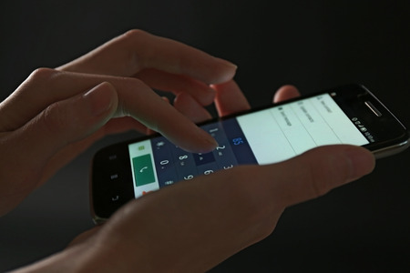 Finger touch number on smartphone to make a call on black backgroundの写真素材