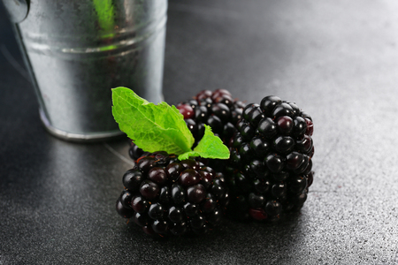 Ripe blackberries with green leaves on dark surface, closeupの写真素材