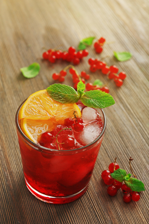 Glass of red currants juice with lemon and ice cubes on wooden table, closeupの写真素材