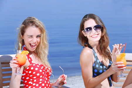Two young girls enjoying cocktails on beachの写真素材