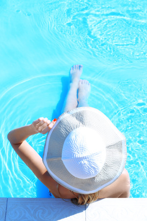 Woman in hat resting in swimming poolの写真素材