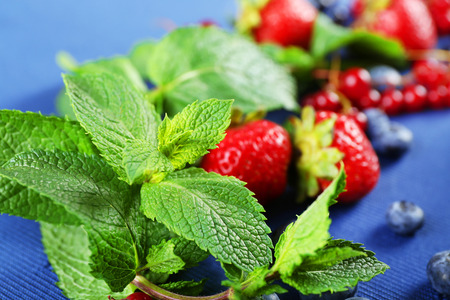 Group of fresh summer berries with mint on blue tablecloth, closeupの写真素材