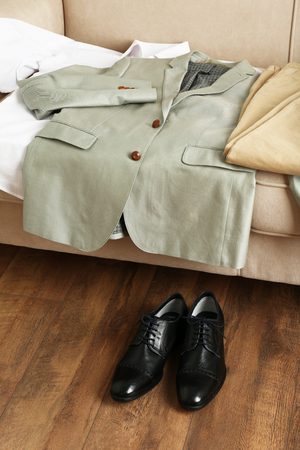 Male clothing on sofa near shoes on floor in roomの写真素材