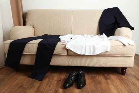 Male clothing on sofa near shoes on floor in roomの写真素材
