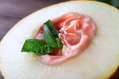 Melon with prosciutto of Parma ham on wooden table, closeupの写真素材