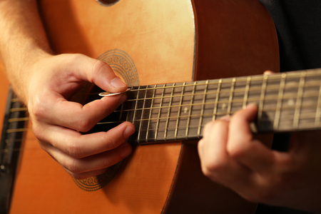 Young musician playing acoustic guitar close up
