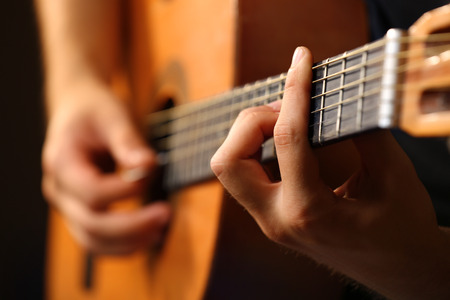 Young musician playing acoustic guitar close up
