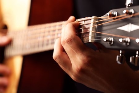 Young musician playing acoustic guitar close up