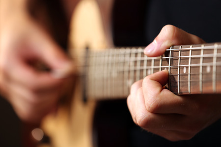Young musician playing acoustic guitar close up