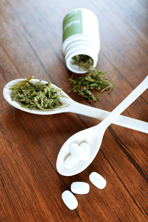Dry medical cannabis and pills in spoons on table close upの写真素材