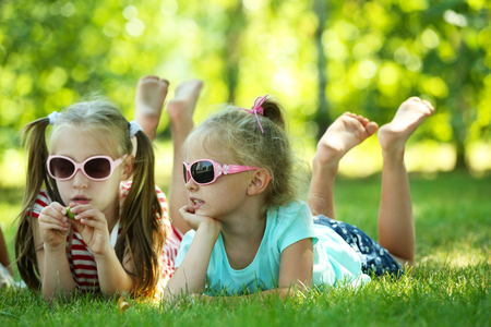 Happy active children lying on green grass in parkの写真素材