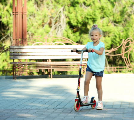 Small girl riding on scooter in parkの写真素材