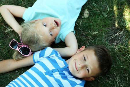Happy active children lying on green grass in parkの写真素材