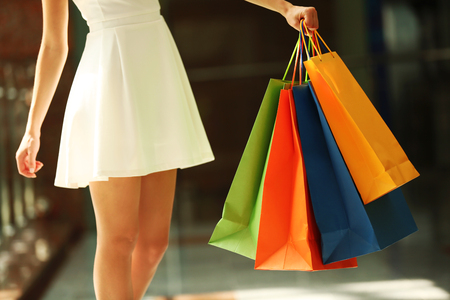Beautiful young woman with bags in shopping centerの写真素材
