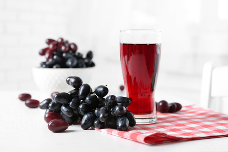 Glass of juice and ripe grapes in bowl on wooden tableの写真素材