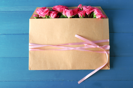 Beautiful roses in envelope on wooden backgroundの写真素材