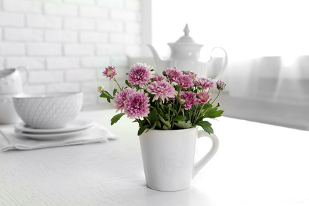 Beautiful flowers in decorative vase on table, on light backgroundの写真素材