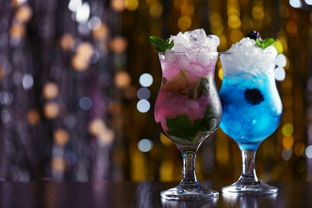 Glasses of cocktails with ice on blurred lights backgroundの写真素材