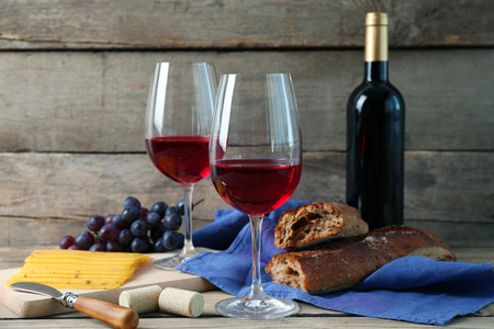 Still life of wine, grape, cheese and bread on rustic wooden backgroundの写真素材