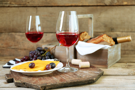 Still life of wine, grape, cheese and bread on rustic wooden backgroundの写真素材
