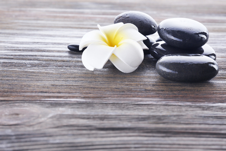 Wet spa stones with flower on wooden backgroundの写真素材