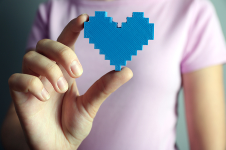 Closeup of plastic puzzle heart in female hand