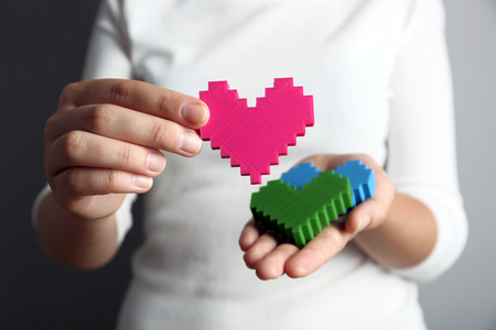 Closeup of plastic puzzle hearts in female hands