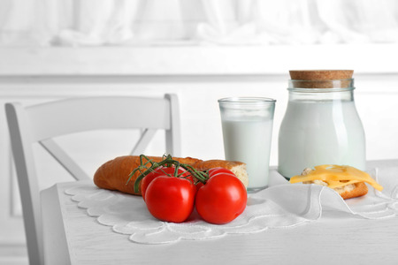 Milk with bread and tomatoes on table in kitchenの写真素材