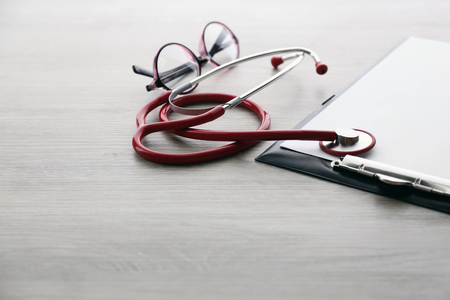 Medical stethoscope with clipboard on wooden table close upの写真素材