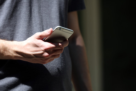 Man holding smart mobile phone outdoors
