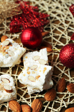 Sweet nougat with almonds and Christmas decoration table close upの写真素材